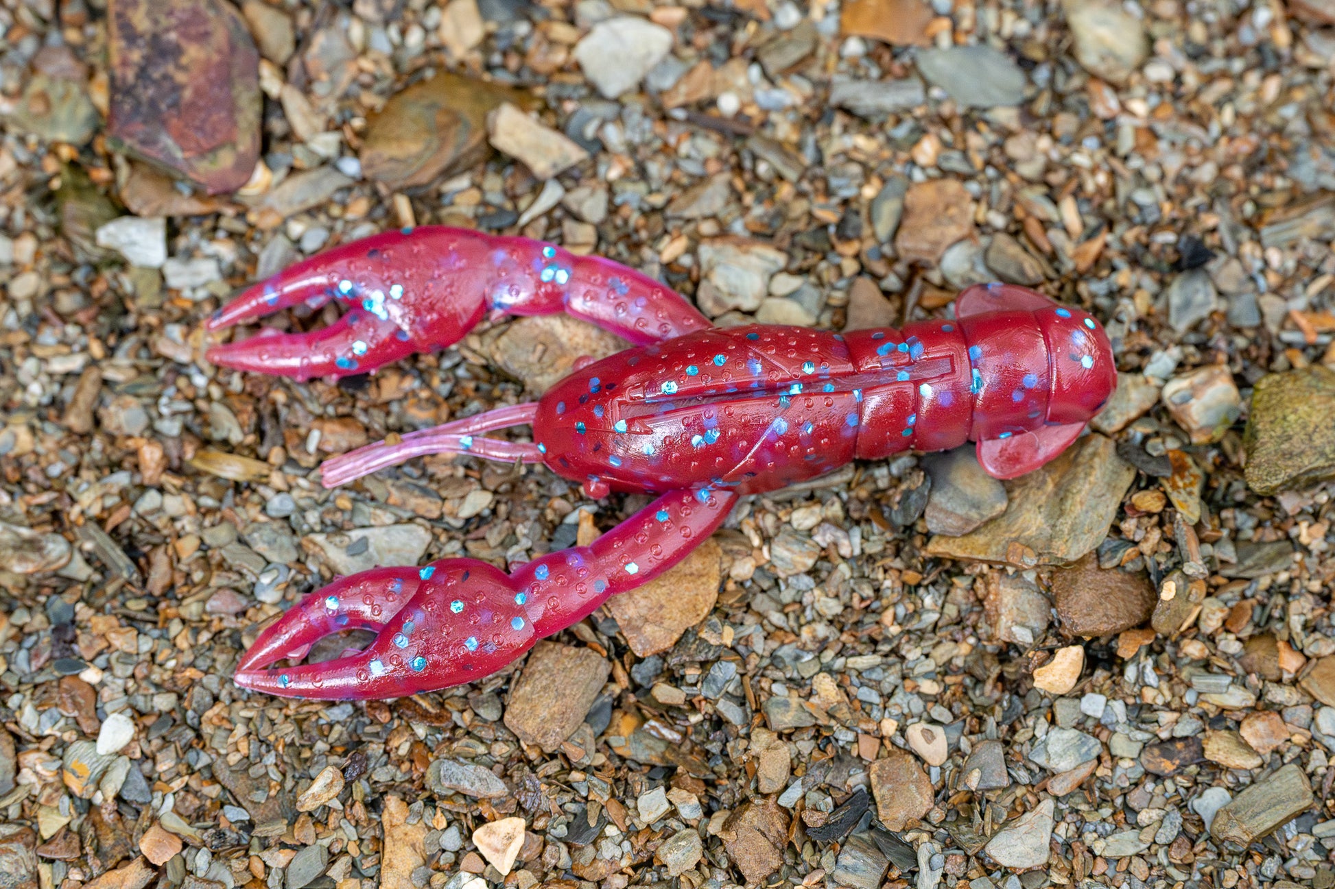 Red plastic crayfish toy on a gravel surface