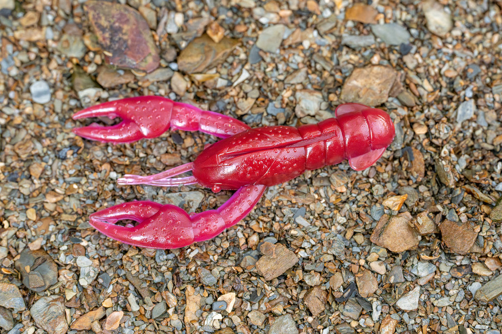 Red plastic crayfish toy on a gravel surface