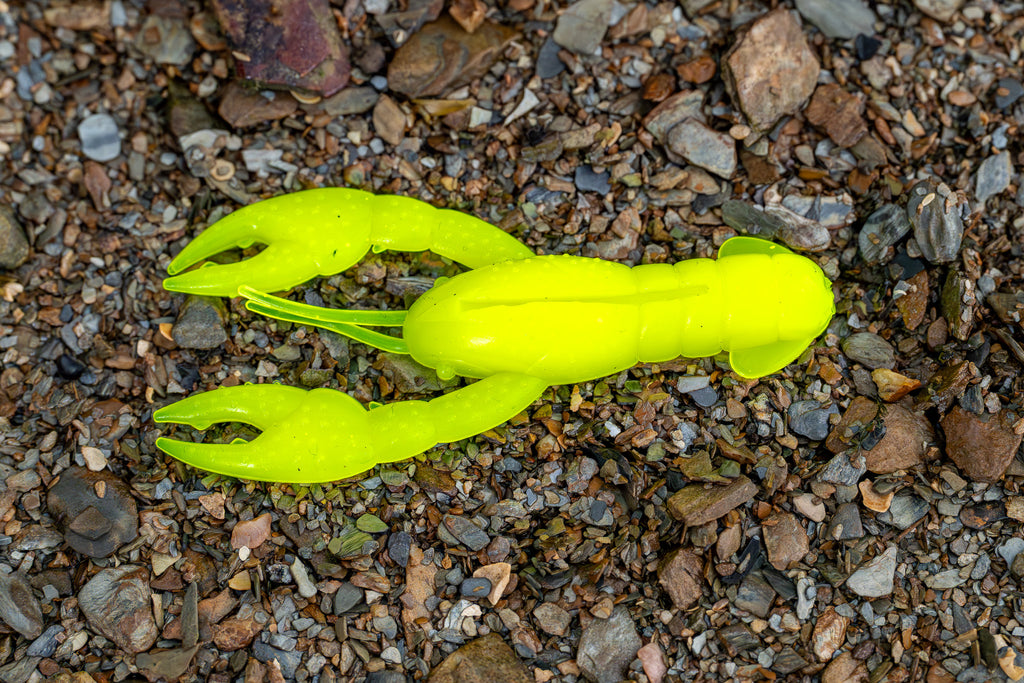 Bright yellow crawfish-shaped fishing lures on a gravel surface