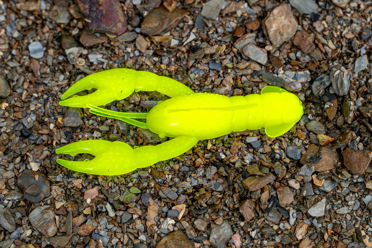 Bright yellow crawfish-shaped fishing lures on a gravel surface