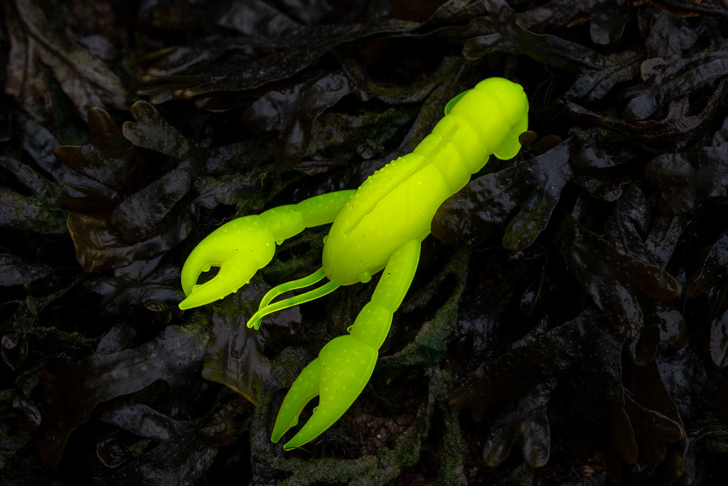 Fluorescent yellow crawfish lure on dark leafy background
