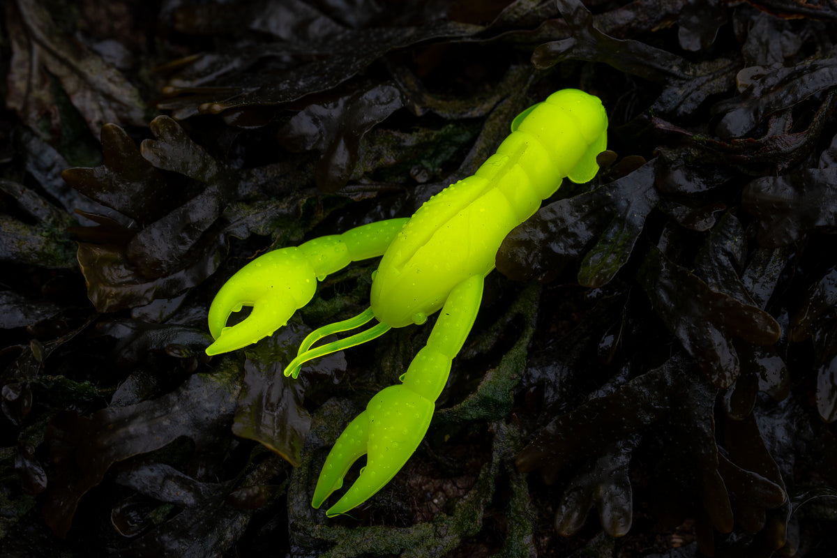Fluorescent yellow crawfish lure on dark leafy background